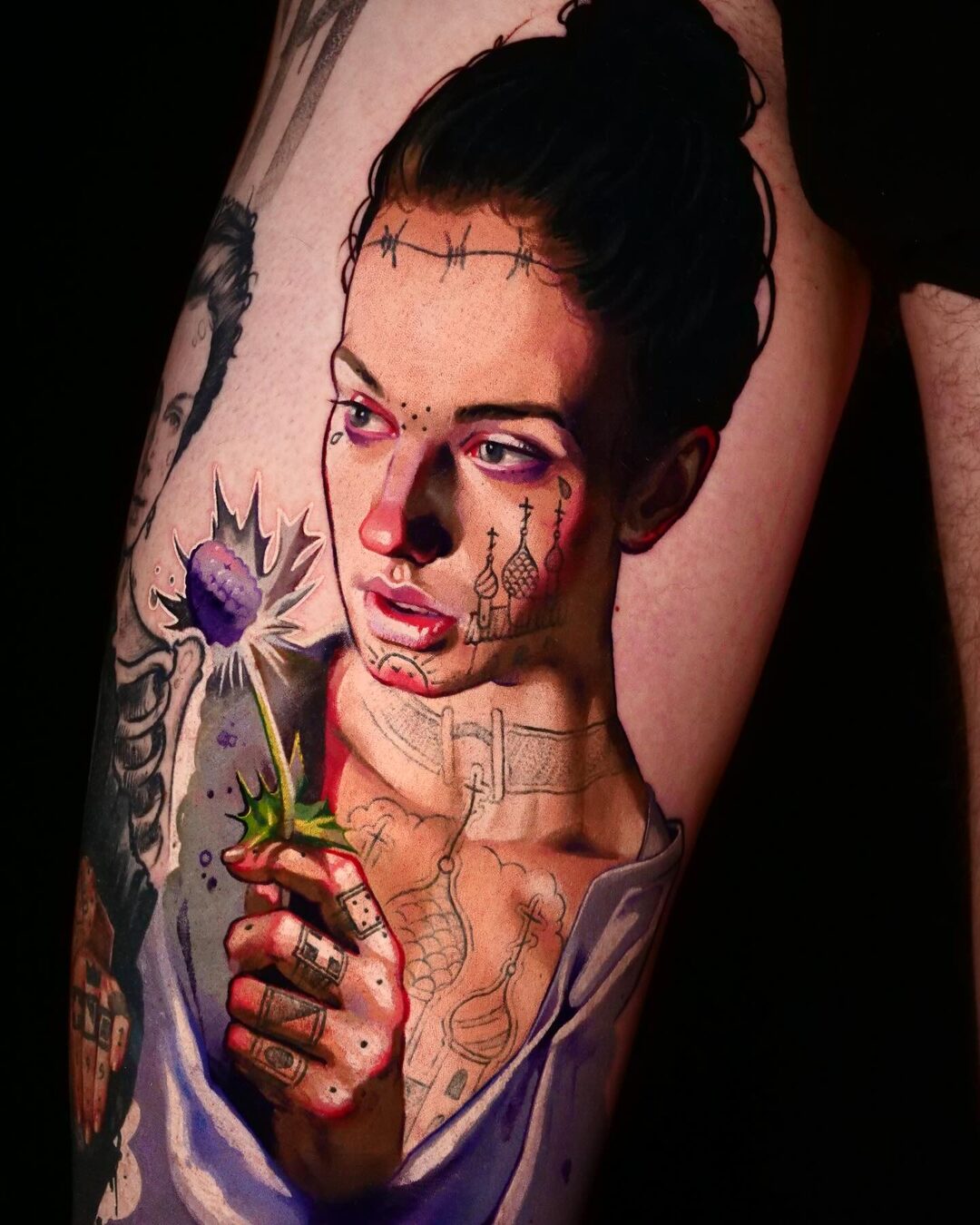 Black-and-grey realism portrait tattoo of a woman with a blue cornflower